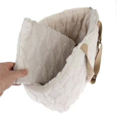 Sac de transport beige en tissu doux avec sangle et coussin intérieur amovible, main tenant le coussin pour montrer l’intérieur du sac.
