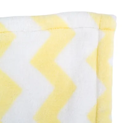 Détail d’un tissu en polaire à motif zigzag jaune et blanc, couture visible sur le bord supérieur.