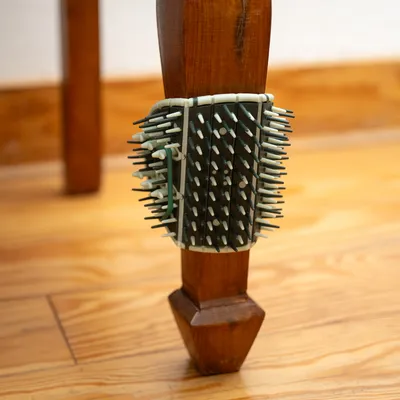 Kratzbürste mit Kunststoffborsten, befestigt an einem Holzstuhlbein. Geeignet für Krallenpflege durch Reiben.