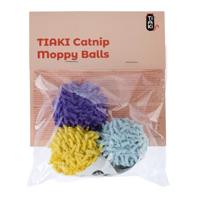 Emballage de 3 balles TIAKI Catnip Moppy Balls, visibles en violet, jaune et bleu clair, avec le nom du produit sur l’étiquette. Matière textile pelucheuse.