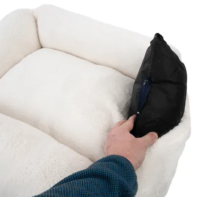 Hand showing removable black inner cushion with zip from a white padded pet bed.