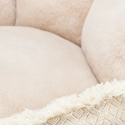 Nahaufnahme eines beigen, weichen Stoffmaterials mit Fransen und gewebtem Muster. Detailansicht des Materials eines Haustierbetts.