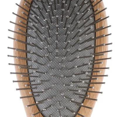 Közelkép egy ovális keféről fa kerettel és fém sörtékkel, szürke alapon.