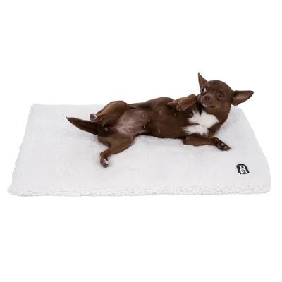 Dog lying on a white, fluffy mat with visible Trixie logo in the corner.