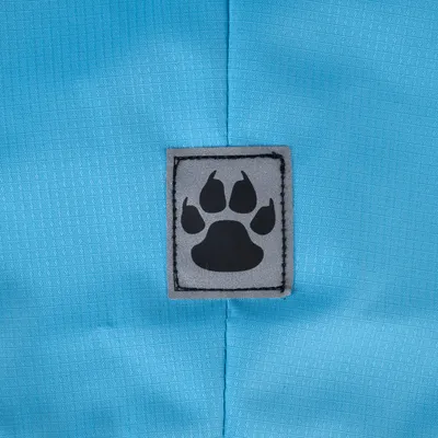 Écusson gris avec empreinte de patte noire sur tissu bleu à motif quadrillé, matière textile visible.