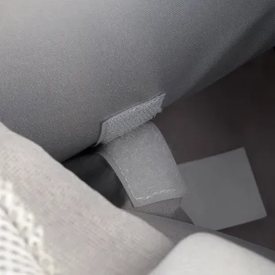 Gros plan sur une fermeture à scratch en tissu gris, cousue sur un article textile. Étiquette blanche visible en arrière-plan.