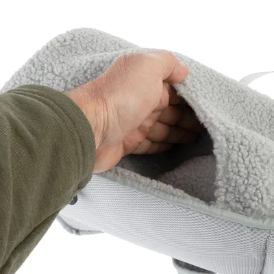 Main insérant dans une poche en tissu polaire gris clair sur un accessoire pour animaux, montrant la texture douce et l’ouverture de la poche.
