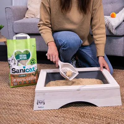 Sanicat Natura Active klontvormend strooisel, 100% groen, plantaardig. Vrouw toont gebruik met strooiselschep in kattenbak.