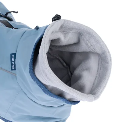 Vue rapprochée d’un manteau pour chien bleu avec doublure polaire grise, étiquette visible « NOMAD TALES » sur le côté.