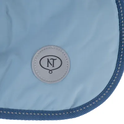 Écusson rond gris avec les lettres NT sur tissu bleu bordé de liseré bleu, aucun autre texte visible.