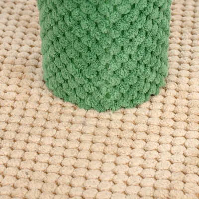 Groene krabpaal met gestructureerd oppervlak op beige tapijt.