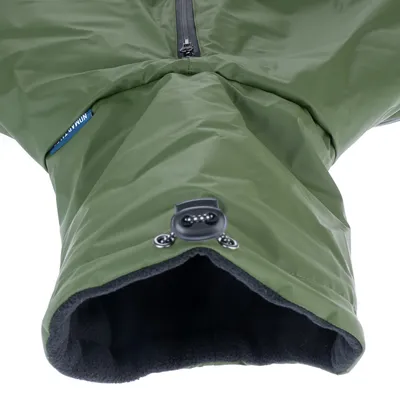 Détail d’un manteau pour chien vert, extérieur en tissu imperméable, doublure intérieure noire en polaire, fermeture éclair visible et cordon de serrage avec stoppeur.