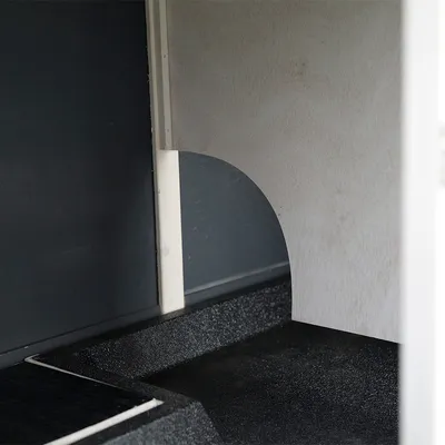 Vista interior de un producto con elementos de madera y plástico, muestra una hendidura curva en un tabique.