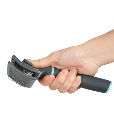 Ruka drží čiernu kefu na starostlivosť o srsť s kovovými štetinami a ergonomickou rukoväťou.