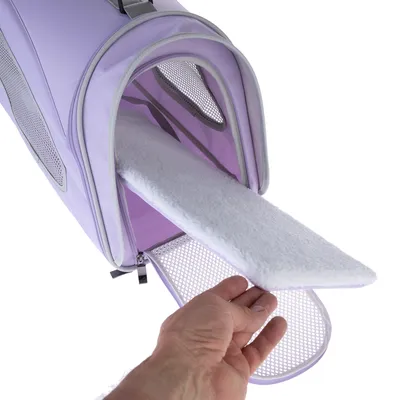 Main retirant un coussin blanc amovible d’un sac de transport violet avec panneaux en maille et fermeture éclair ouverte à l’avant.