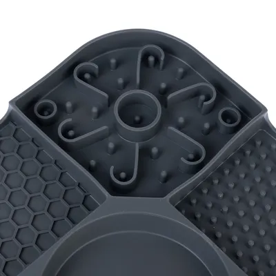 Vue rapprochée d’un plateau en plastique gris avec plusieurs zones à motifs : alvéoles, picots et spirales. Aucun texte ou marque visible.