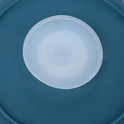 Közelkép egy kék műanyag fedélről fehér betéttel, látható 'Made in China' felirattal.