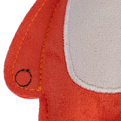 Close-up of an orange fabric toy with white stitching and a black circle on the surface.