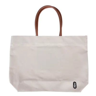 Bolsa de transporte Tiaki de tela blanca con asas marrones, adecuada para transportar objetos.