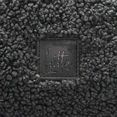 Designed by Lotte – étiquette sur tissu bouclé foncé, nom de la marque visible au centre de l’image