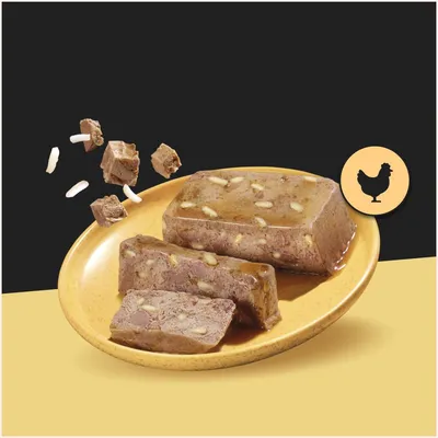 Chunky wet food with visible pieces of rice on a plate, next to it a chicken symbol indicating the type of meat. Chunky wet food with visible pieces of rice on a plate, next to it a chicken symbol indicating the type of meat.