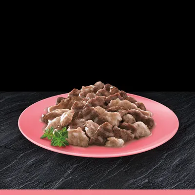 Bocconcini di carne in salsa serviti su un piatto rosa, con decorazione di erbe fresche visibile nell'angolo del piatto.