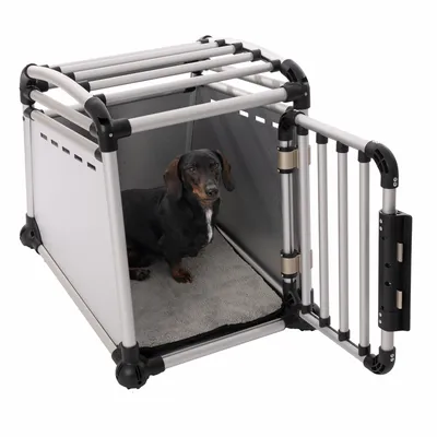 Transportbox aus Metall und Kunststoff mit offener Tür, grauer Innenmatte und einem kleinen Hund darin.