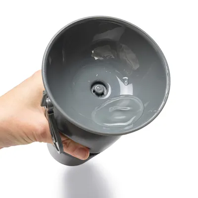 Grauer Wasserspender mit integriertem Ventil, gehalten in einer Hand. Zeigt die Funktion des Ausgiessens von Wasser.