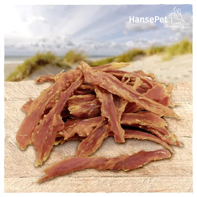 Lamelles de viande séchée sur une planche en bois, marque HansePet visible en haut à droite de l’image.
