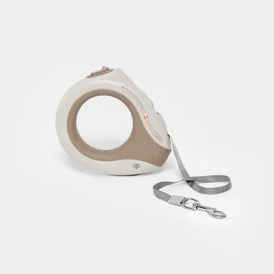 Guinzaglio avvolgibile beige-grigio con manico ergonomico e moschettone argento, adatto per pet. Logo visibile 'NT' sul guinzaglio.