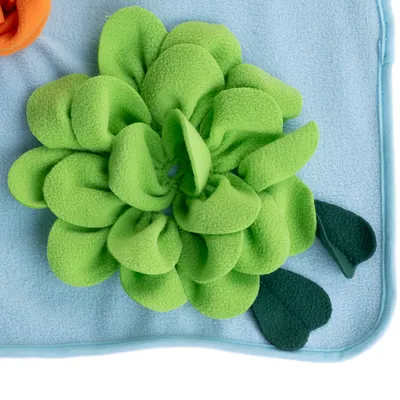 Lyseblåt fleece med grønt blomstermønster af stof, dekorative blade på siden. Detaljebillede af designet.