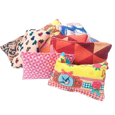 Комплект от малки възглавнички с различни цветни шарки и мотиви, включително геометрични фигури, цветя и птица. Видими са текстилни материали.