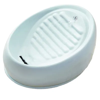 Weisser Trinkbrunnen mit gerillter Oberfläche und Wasserstrahl aus einer kleinen Öffnung.