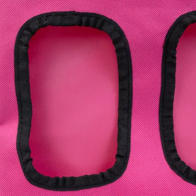 Vista detallada de un material textil rosa con dos aberturas rectangulares bordeadas de tela negra.