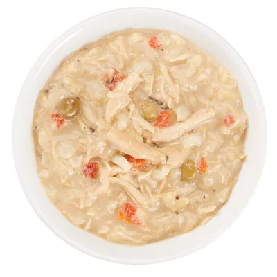 Nourriture humide pour animaux dans une assiette blanche, morceaux de viande en sauce avec légumes visibles (carottes, pois).