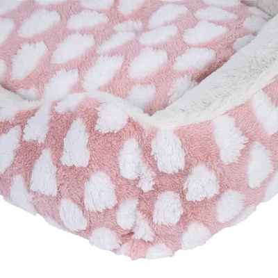 Nahaufnahme eines rosa Haustierbetts mit weissen Punkten und weichem Plüschmaterial.