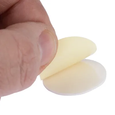 Detailní záběr na ruku, která odlepuje samolepicí kulatou fólii. Ukazuje funkci produktu jako lepicí plochy.