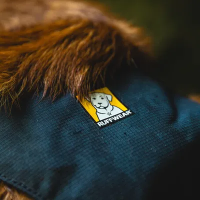 Ruffwear-logo op donkerblauwe stof met bruine vacht op de achtergrond.