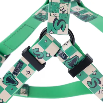 Vihreä valjas Slytherin-kuosilla, shakkiruutukuviolla, mustilla soljilla ja metallirenkaalla. Designissa käärmeitä ja tähtiä.