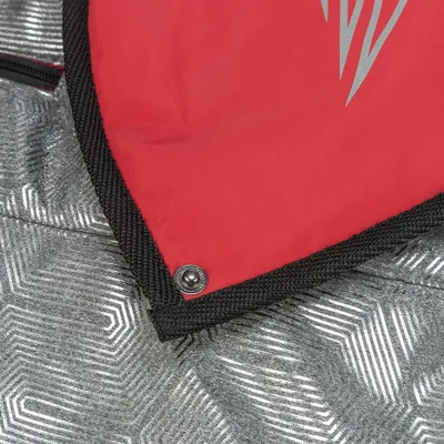 Detailansicht eines roten und silbernen Materials mit Druckknopf und geometrischem Muster.