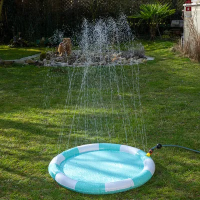 Pyöreä vesilelu sprinkleritoiminnolla, liitetty puutarhaletkuun. Vesiruiskut suihkuavat ilmaan, sopii puutarhaan.