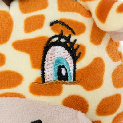 Nærbillede af plyslegetøj med broderet øje og orange-gult girafmønster.
