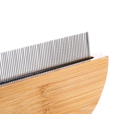 Peigne avec manche en bois et dents métalliques rapprochées, vue de près sur la partie supérieure du produit.