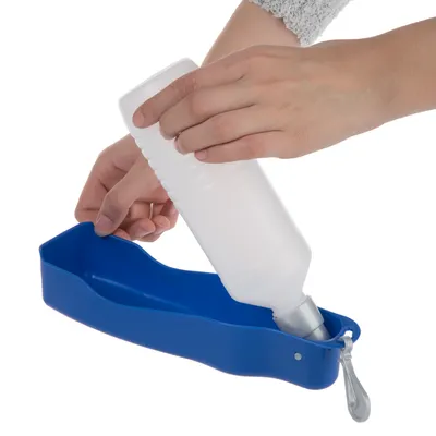 Hand zeigt, wie eine weisse Wasserflasche in eine blaue tragbare Trinkschale für Haustiere eingeführt wird.