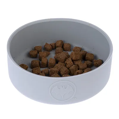 Ciotola grigia per alimenti con logo Batman, riempita con crocchette marroni.