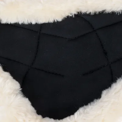 Gros plan sur un tissu noir matelassé entouré de fausse fourrure blanche, matériaux visibles d’un produit pour animaux.