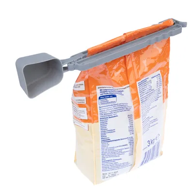 Szürke adagolókanál zárócsipesszel egy narancssárga 3 kg-os száraztáp csomagoláson. Látható összetevők és tápértékjelzés a csomagoláson.