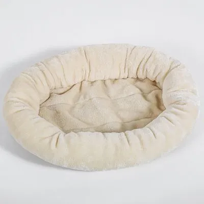 Ovale beige huisdierenmand van zachte stof met opstaande rand, geschikt als ligplek voor hond of kat. Geen merknaam of extra details zichtbaar.