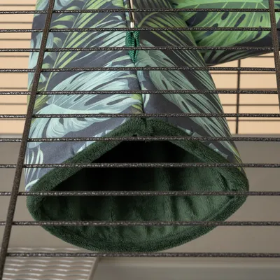 Hamaca con estampado de hojas verdes y forro interior suave, sujeta a jaula metálica mediante ganchos.