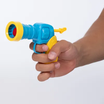 Hand hält eine blaue und gelbe Spielzeugpistole mit rotem Ball im Lauf, geeignet für interaktives Spielen.